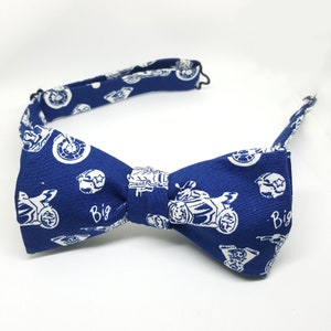 May include: A blue bow tie with a white pattern of motorcycles and the word "Big" repeated on each side.