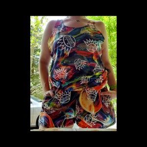 May include: A colorful tank top and shorts set with a psychedelic swirl pattern and white cartoon faces. The faces have a crown of spikes and are repeated throughout the fabric.