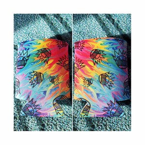 May include: A colorful tie-dye can cooler with a black and white graphic of a smiling face with a crown. The cooler is made of neoprene and is designed to keep drinks cold.