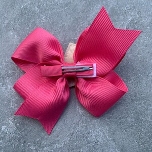 Puede incluir: Un gran lazo rosa con un clip de cocodrilo plateado. El lazo est&aacute; hecho de cinta de grosgrain y est&aacute; atado en un estilo cl&aacute;sico.