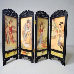 Peut inclure: Écran pliable à quatre panneaux avec des cadres laqués noirs. Chaque panneau présente une peinture d'une femme en tenue asiatique traditionnelle. L'œuvre d'art est placée sur un fond jaune avec des accents floraux. L'écran est un objet décoratif.