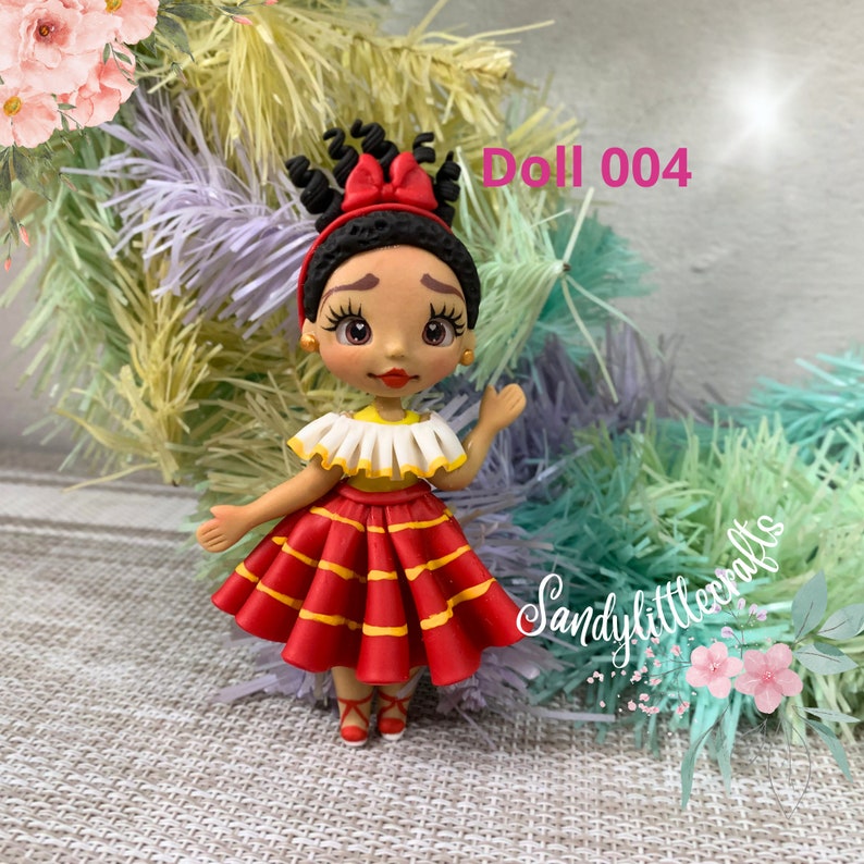 May include: A handmade doll with dark curly hair and a red bow. The doll is dressed in a red and yellow skirt, a white and yellow top, and red shoes. The text "Doll 004" is visible.