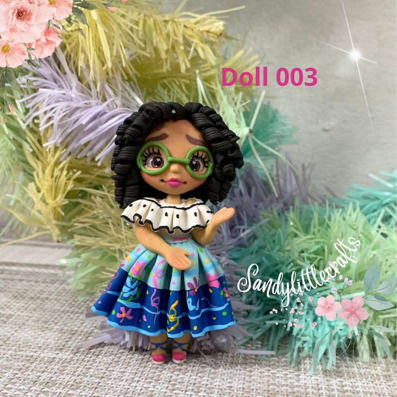 May include: A handmade doll featuring black curly hair, green spectacles, and a vibrant dress. The doll's top is white with black polka dots, and the skirt is blue with floral and ribbon patterns. The text "Doll 003" is displayed.