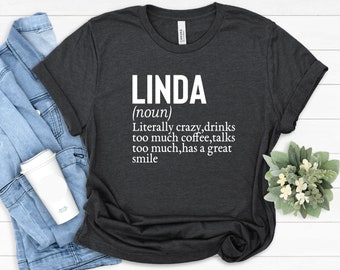 Può includere: Una maglietta grigio scuro con testo bianco che recita "LINDA (nome) Letteralmente pazza, beve troppo caffè, parla troppo, ha un grande sorriso."