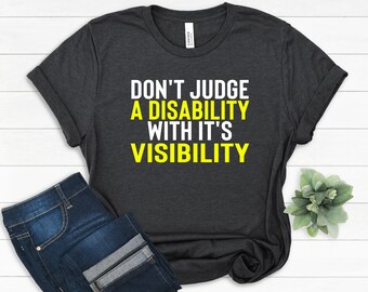 Puede incluir: Una camiseta gris oscuro con el texto "Don't Judge a Disability with it's Visibility" en letras blancas y amarillas.