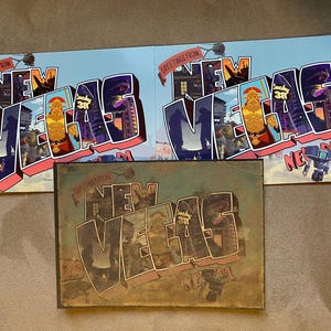 May include: Three vintage-style postcards with the text "Greetings from New Vegas, Nevada" in a colorful, cartoonish font. The postcards feature a variety of characters and buildings from the video game Fallout: New Vegas.