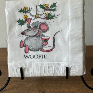 May include: A package of white paper napkins featuring a cartoon mouse holding a drink, with holly and lights. The word "WOOPIE" is above the mouse, and "CONTEMPO" is embossed on the border.