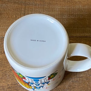 Puede incluir: Taza de cer&aacute;mica blanca con un dise&ntilde;o colorido y el texto "MADE IN KOREA" en la parte inferior.