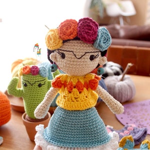Op de afbeelding: Gehaakte pop met een bloemenkrans, geel topje, blauwe rok en rode schoenen. De pop draagt een traditionele Mexicaanse outfit.