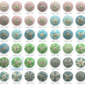 May include: A selection of decorative ceramic cabinet knobs in shades of pink, blue, and green. Each knob has a unique floral or geometric pattern and a silver-coloured metal base. The knobs are labelled with the code MOM followed by a number.