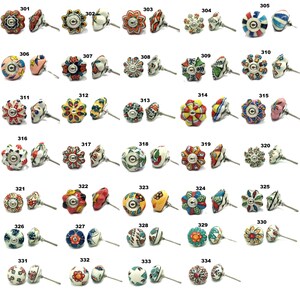 Op de afbeelding: Een verzameling decoratieve keramische kastknoppen in diverse bloemen- en geometrische ontwerpen. De knoppen hebben een reeks kleuren, waaronder rood, blauw, geel en groen, met metalen beslag. Elke knop is uniek en biedt een gevarieerde selectie.