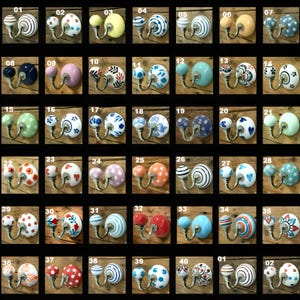 Puede incluir: Una colección de ganchos de pared decorativos de cerámica en varios colores y patrones. Los diseños incluyen rayas, lunares, florales y formas abstractas. Cada gancho tiene una base metálica para el montaje. Los ganchos están montados sobre madera.