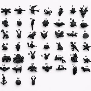 Puede incluir: Una colección de 45 tiradores de armario de metal negro en diversas formas de animales y objetos, incluyendo una libélula, caballito de mar, cabeza de ciervo, ardilla, loro y pulpo. Cada tirador es un acento decorativo único.
