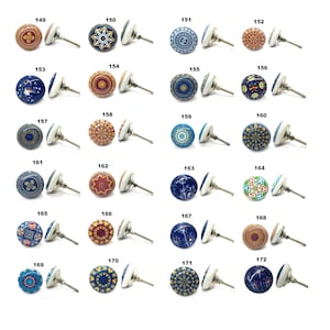 Op de afbeelding: Een verzameling decoratieve kastknoppen met diverse kleurrijke patronen. Elke knop heeft een keramisch ontwerp met een witte basis en een metalen schroef. De ontwerpen omvatten bloemen-, geometrische en hemelse motieven.