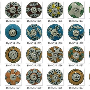 Op de afbeelding: Een verzameling decoratieve keramische kastknoppen in diverse kleuren en patronen. Elke knop heeft een uniek bloemen- of geometrisch ontwerp met een metalen basis. De afbeelding bevat de productcodes EMBOSS 1001 t/m EMBOSS 1040.