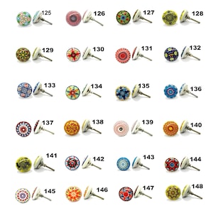 Op de afbeelding: Een verzameling decoratieve keramische kastknoppen met diverse kleurrijke patronen. Elke knop heeft een witte basis, een decoratieve voorkant en een zilveren metalen steel. De knoppen zijn genummerd van 125 tot 148.