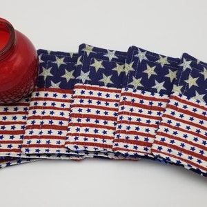 Peut inclure: Ensemble de six dessous-de-verre en tissu avec un motif de drapeau américain. Les dessous-de-verre sont en tissu bleu avec des étoiles blanches et un tissu rayé rouge et blanc.