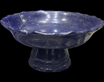 May include: A blue lapis lazuli bowl with a scalloped edge and a pedestal base. The bowl is made of natural stone and has a unique, marbled pattern.