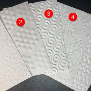 May include: Five different white embossed paper sheets with various patterns. The patterns include a small geometric design, a pattern of small circles, a swirl pattern, a pattern of small circles in a geometric design, and a diagonal line pattern.