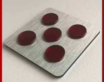 May include: A rectangular, brushed metal plate with five circular, translucent, ruby-red pieces arranged in a grid pattern. The text "MADE IN GERMANY" is at the top. The website address www.opleprops.com is at the bottom.