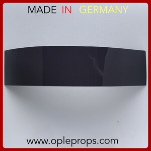 May include: A black plastic sign with rounded edges and the text "MADE IN GERMANY" in white letters. The sign is on a white background.