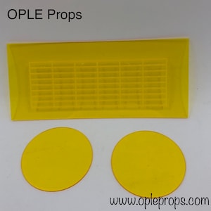 Peut inclure: Accessoires en acrylique jaune, comprenant une pièce rectangulaire avec un motif quadrillé et deux pièces circulaires. Le texte "OPLE Props" est dans le coin supérieur gauche et "www.opleprops.com" dans le coin inférieur droit.