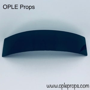 May include: A black, curved, plastic prop for use in photography or film. The prop is made of a smooth, glossy material. The prop is about 10 inches long and 2 inches wide. The prop is a simple, versatile tool that can be used to create a variety of effects.