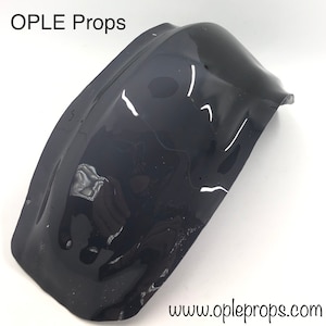 May include: Black plastic prop for a movie or play. The prop is shaped like a curved, half-dome.