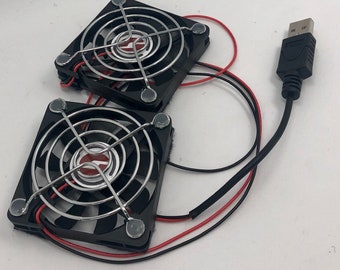 May include: Two black computer cooling fans with silver wire mesh grills and a USB connector. The fans are connected by wires and have adhesive backing. The text "OPLE Props" is visible in the top left corner of the image. The text "www.opleprops.com" is visible in the bottom right corner of the image.