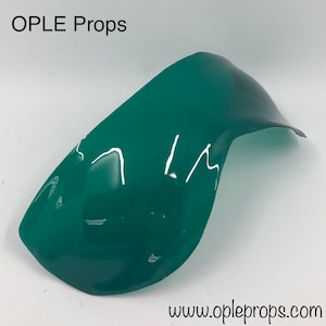 May include: A curved, glossy, teal-green prop with the text "OPLE Props" at the top and "www.opleprops.com" at the bottom. The prop has a smooth, reflective surface and a rounded shape, likely for a costume or theatrical use.