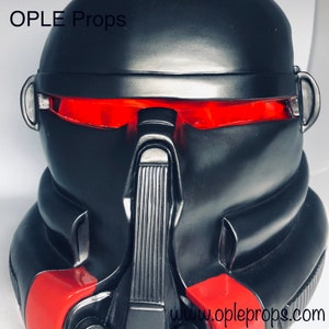 May include: A black helmet with red visor accents. The helmet has a textured surface and a black visor. The text "OPLE Props" is visible at the top of the image. The text "www.opleprops.com" is visible at the bottom of the image.