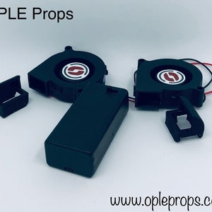 May include: Black Ople Props components, including two fan units with red and white accents, a black battery pack, and two small black brackets. The text "OPLE Props" and "www.opleprops.com" are visible.