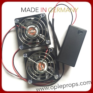 May include: Two small black cooling fans with silver wire mesh grilles and red and black wires connected to a black battery pack. The fans are labeled "MADE IN GERMANY" and the battery pack has the website "www.opleprops.com" printed on it.