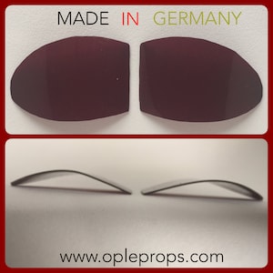 May include: Two dark burgundy-colored, curved, oval-shaped pieces. The top of the image has the text "MADE IN GERMANY" in red and green. The bottom of the image has the website address "www.opleprops.com".
