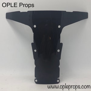 May include: Black plastic prop for a movie or television show. The prop is shaped like a T and has several holes in it. The prop is made by OPLE Props and the website is www.opleprops.com.