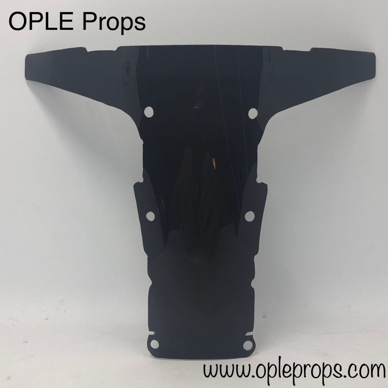 May include: Black plastic prop for a movie or television show. The prop is shaped like a T and has several holes in it. The prop is made by OPLE Props and the website is www.opleprops.com.