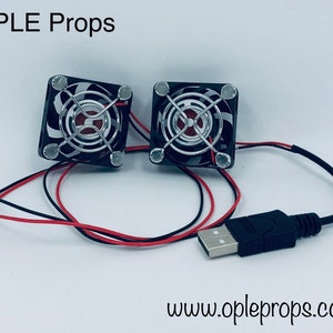 May include: Two small black USB powered fans with silver wire grills and black and white patterned housings. The fans are connected to a black USB cable.