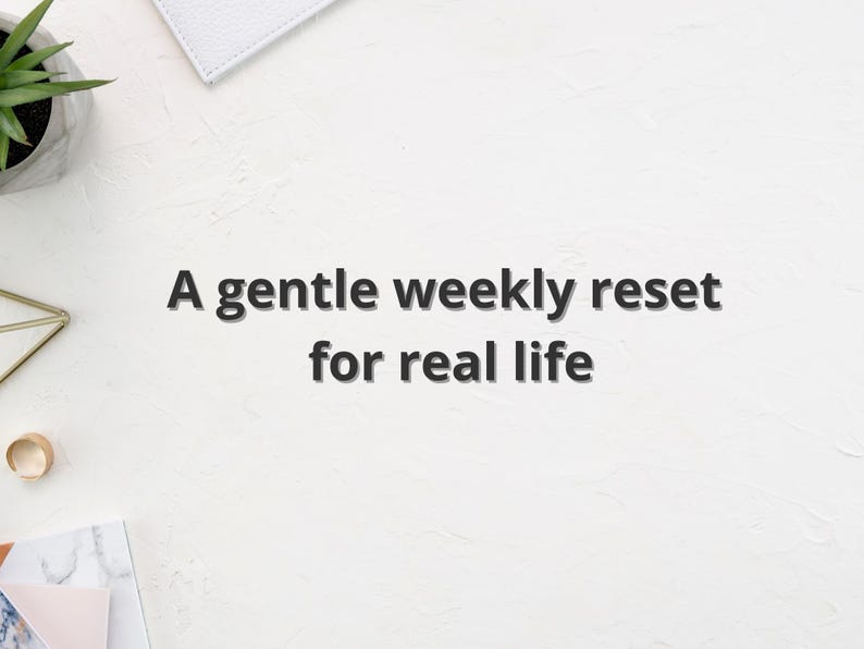 May include: White textured surface with the text "A gentle weekly reset for real life." A small succulent plant in a gray pot, a gold geometric object, and a white notebook are visible.