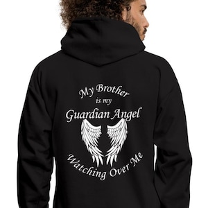 Op de afbeelding: Zwarte hoodie met rits, met witte tekst die "My Brother is my Guardian Angel Watching Over Me" zegt en een paar witte engelenvleugels.