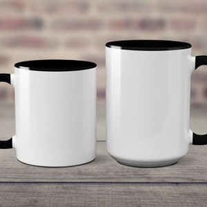 May include: Two white ceramic mugs with black rims and handles. The mug on the left is smaller than the mug on the right.