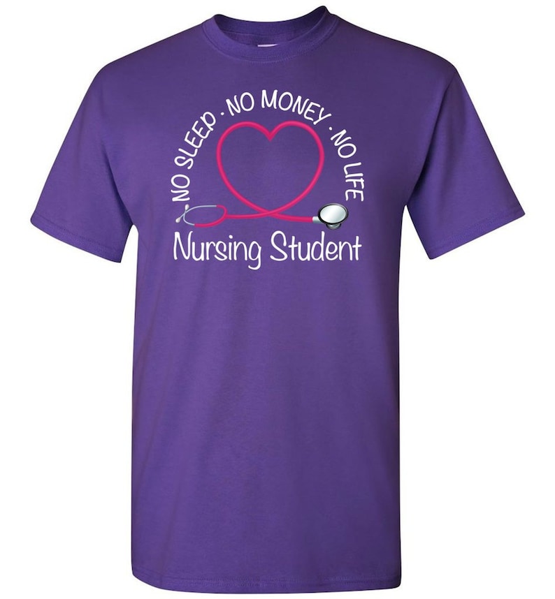 Peut inclure: T-shirt violet avec un motif blanc. Le motif comprend le texte "NO SLEEP - NO MONEY - NO LIFE" autour d'un st&eacute;thoscope rose en forme de c&oelig;ur. Le texte "Nursing Student" est en dessous.