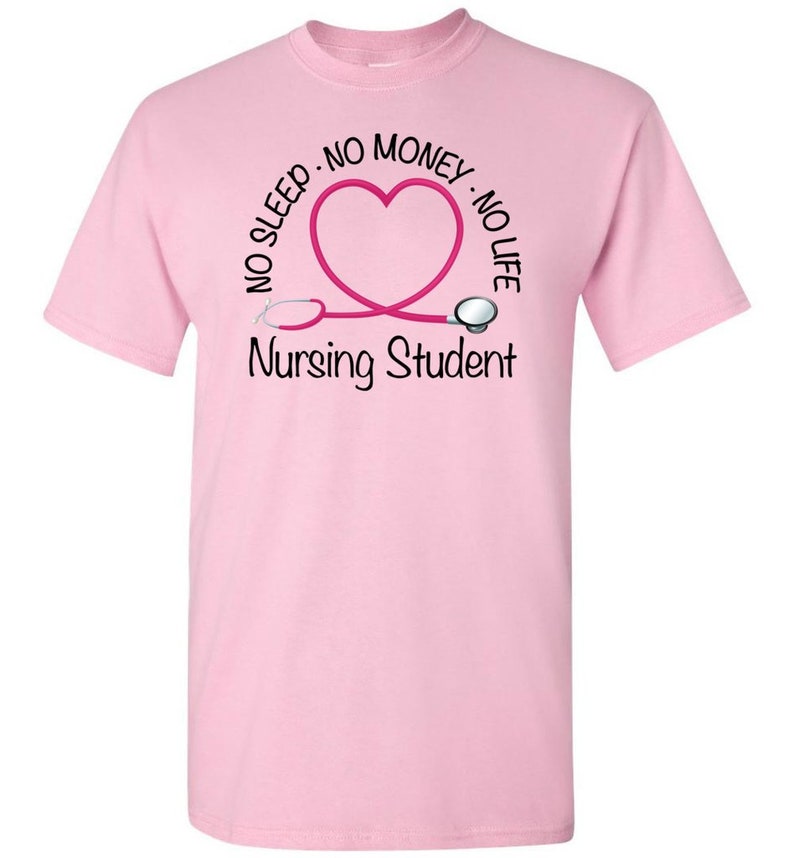 Peut inclure: T-shirt rose clair avec un motif pour &eacute;tudiants en soins infirmiers. Le motif comprend un st&eacute;thoscope rose en forme de c&oelig;ur, avec les mots "NO SLEEP, NO MONEY, NO LIFE" au-dessus du c&oelig;ur et "Nursing Student" en dessous.