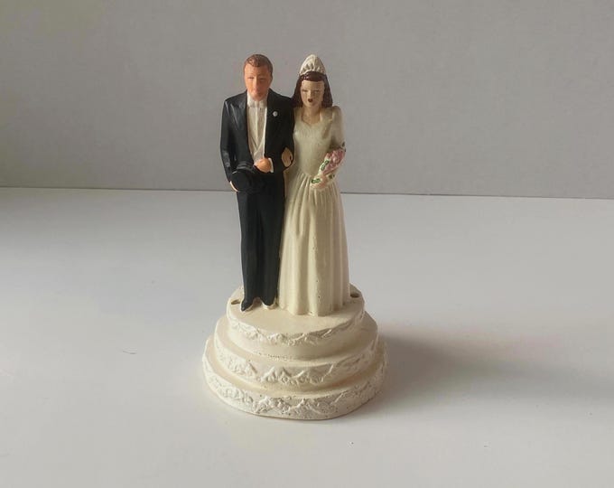 1950 Bride and Groom Chalkware Cake Topper standing on Tiered Base with faux flowers and floor length veil