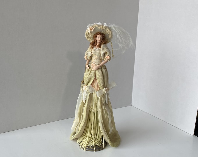 Victorian 12" tall tassel doll in a soft Moss green with long, ornate gown,  wide brim hat on antiqued brass colored stand