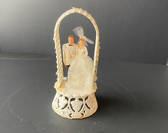 1959 Plastic Bride and Groom Cake Topper surrounded with a plastic pearlesque arch on plastic filigree floral base from Coast Novelty