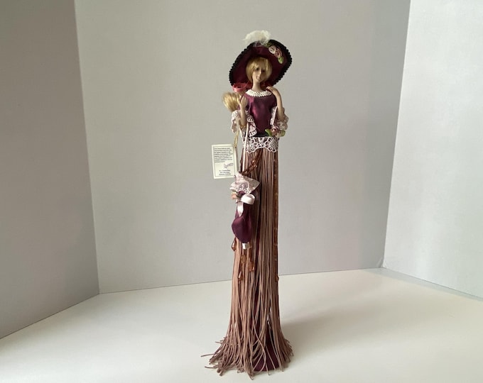 Victorian 14 1/2" tall tassel doll in mauve with long gown, ornate parasol and covered stand with original tag
