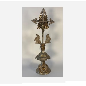 May include: An antique brass crucifix with a detailed design. The cross features ornate detailing, with a figure of Jesus Christ and decorative elements. Two small angel figures are positioned below the cross. The base has a floral design.