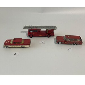 May include: Three die-cast metal toy emergency vehicles labeled A, B, and C. Vehicle A is a red and white fire chief car. Vehicle B is a red fire truck with a silver ladder. Vehicle C is a red station wagon with a fire department emblem on the side.