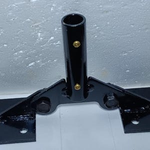 以下が含まれることがあります： 垂直のチューブと2つの水平プレートを備えた黒い金属ブラケット。ブラケットはボルトで固定されており、光沢のある仕上げです。垂直チューブには2つの金色のリベットが付いています。