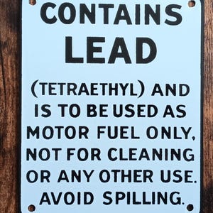 May include: White metal sign with black text that reads "CONTAINS LEAD (TETRAETHYL) AND IS TO BE USED AS MOTOR FUEL ONLY, NOT FOR CLEANING OR ANY OTHER USE. AVOID SPILLING."